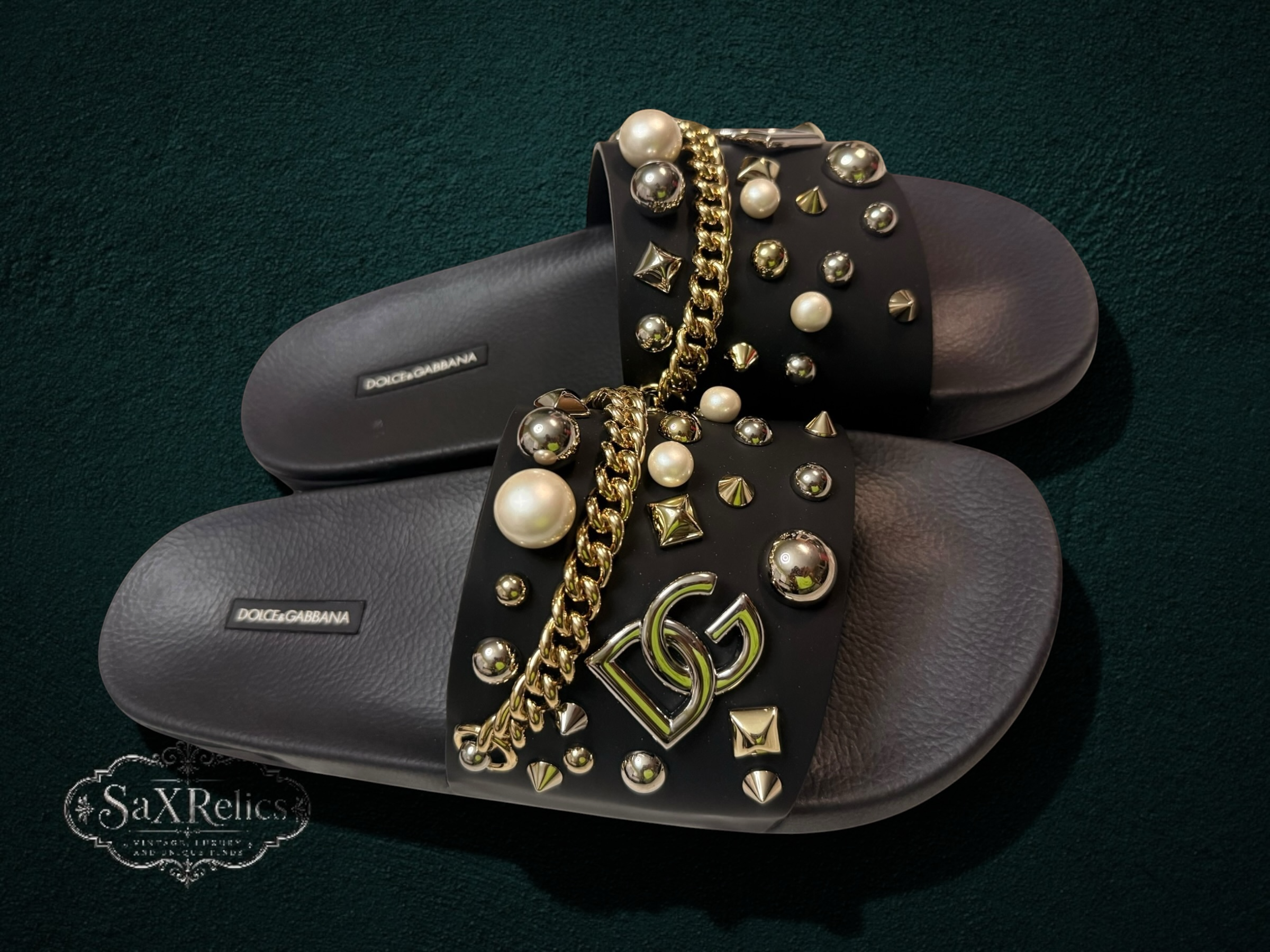 My Store Dolce & Gabbana black rubber slide sandals with pearl, gold stud, and chain embellishments. Features DG logo.